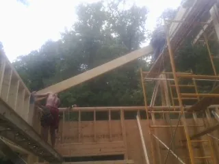 Carpenter raising a rafter beam on a new second story frame in Bainbridge